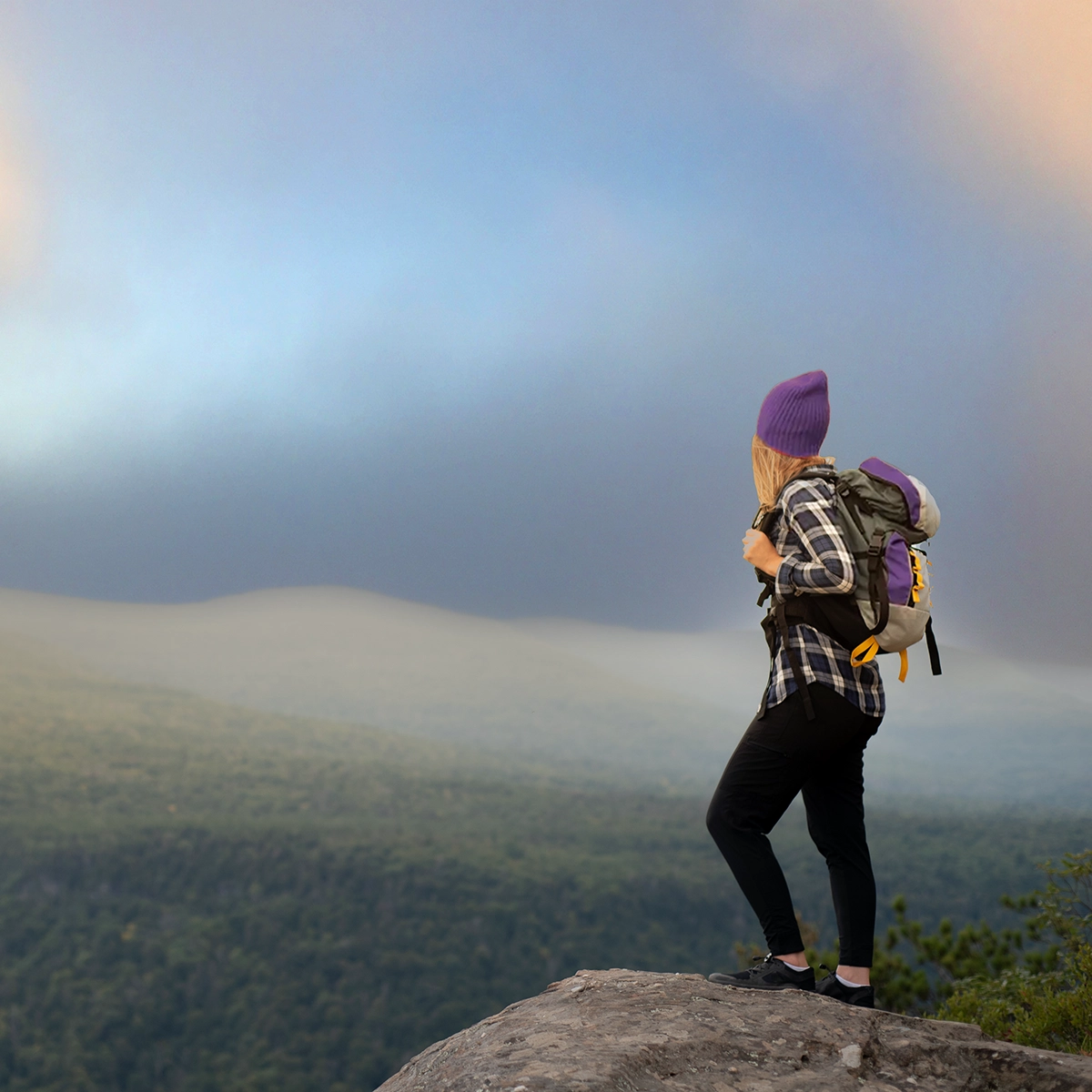 A young woman hiking alone through mountains with a backpack.